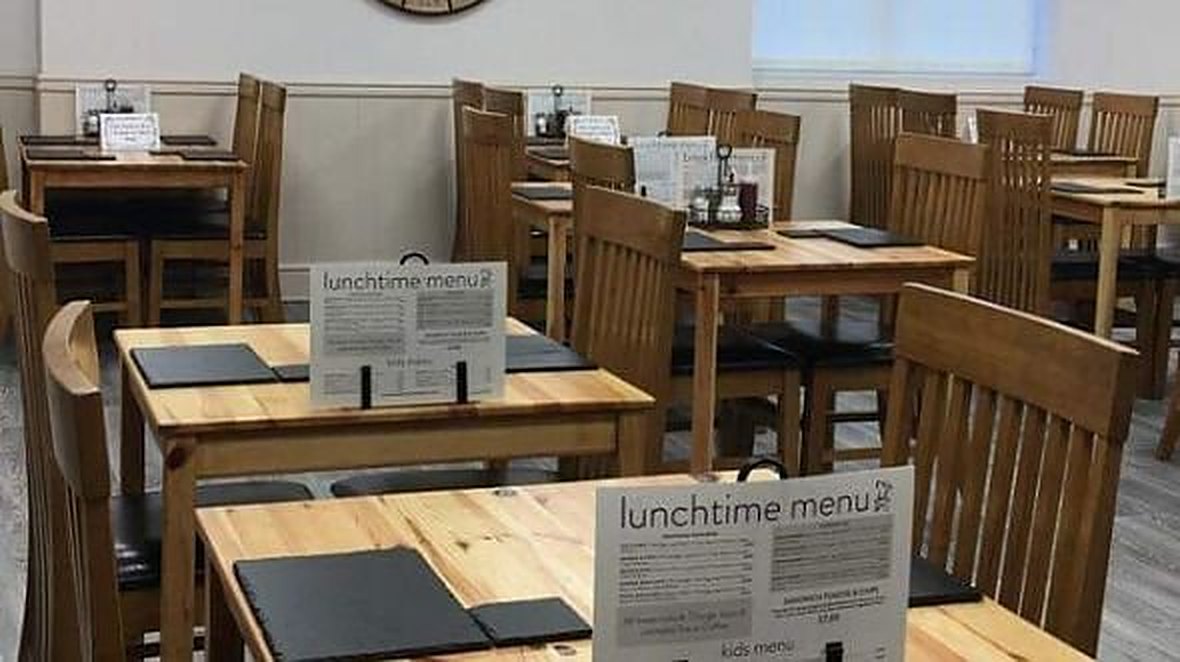 Inside Breaktimes: pine tables with slate place mats, wooden chairs, and lunchtime and kids’ menu cards on each table